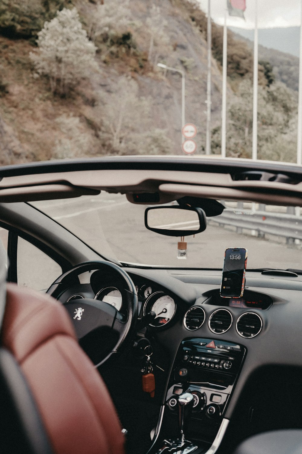 a car driving down a road next to a mountain