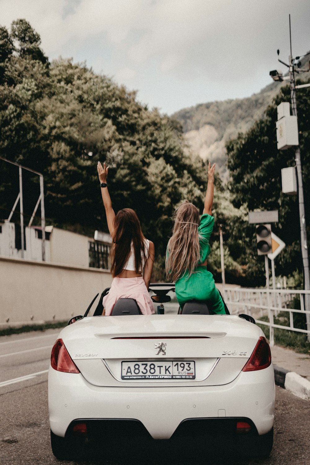 two women sitting in the back of a white sports car