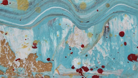 Abstract artwork featuring a sweeping, wavy pattern predominantly in shades of turquoise. Dotted with red and gold splatters across the canvas, resembling a dynamic flow reminiscent of an ocean wave. Accents of white and hints of pale brown create texture and depth.