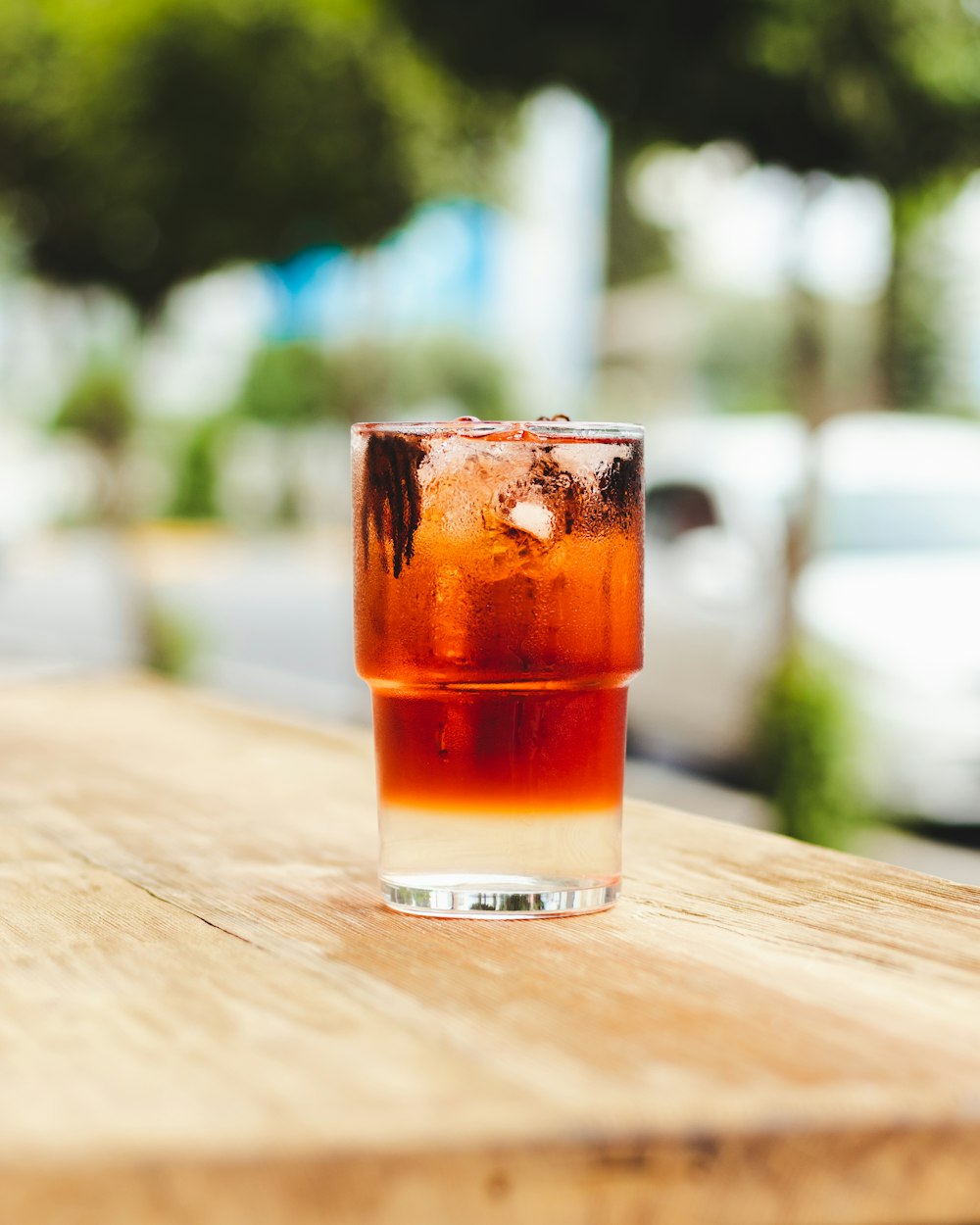 a glass of soda sitting on top of a wooden table