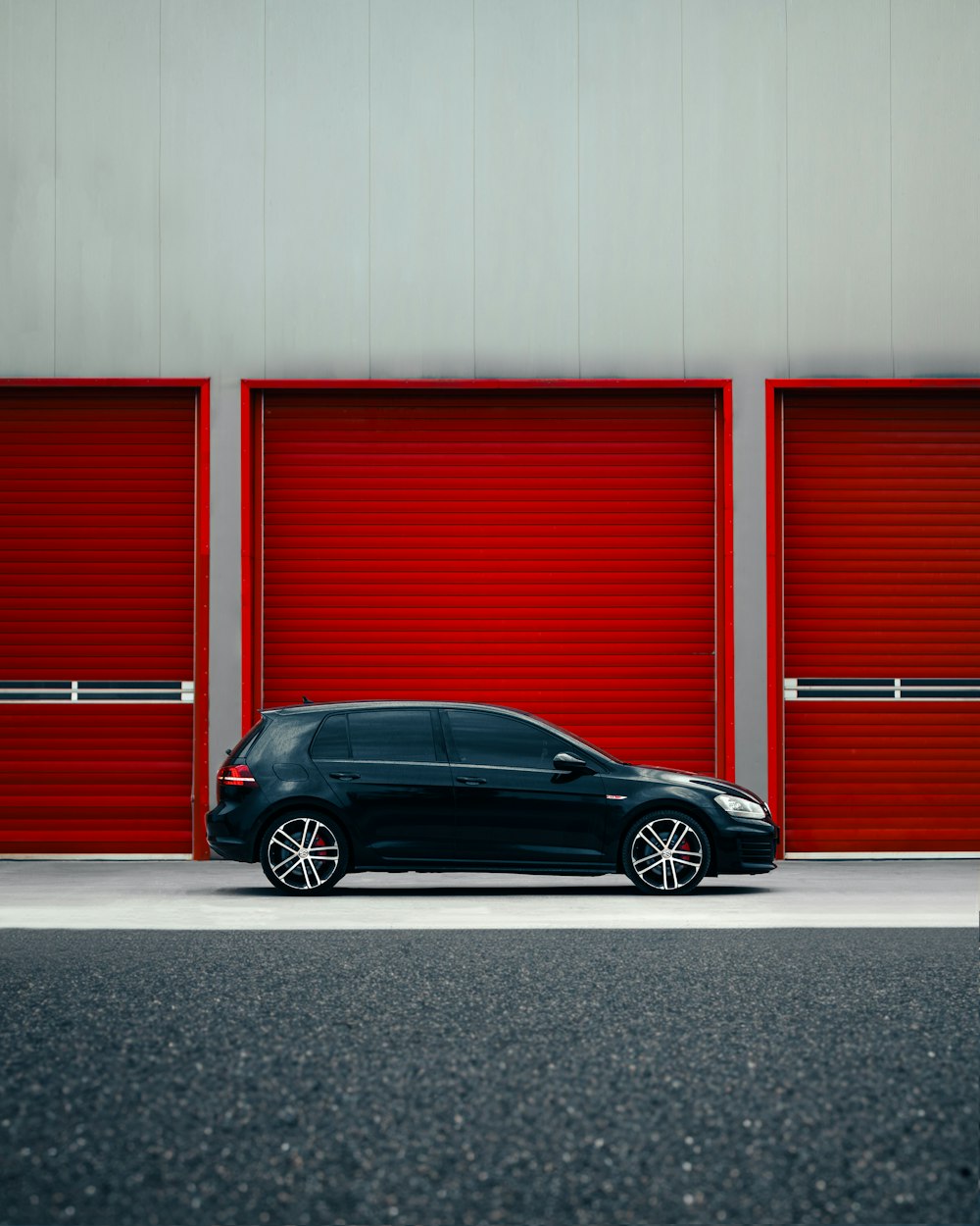 a black car parked in front of a red garage door