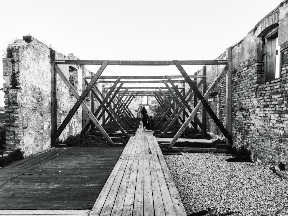 a black and white photo of a person standing on a bridge