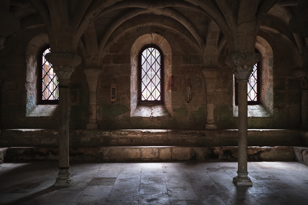 a room with three windows and a stone floor