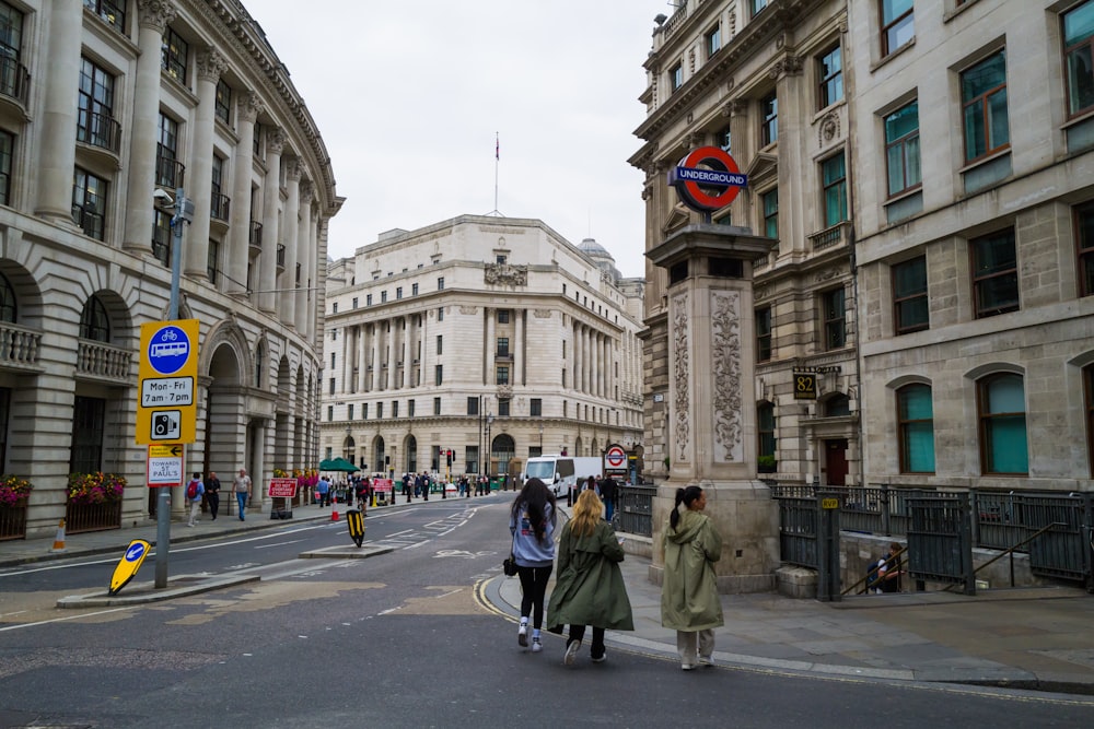 a group of people walking down a street next to tall buildings