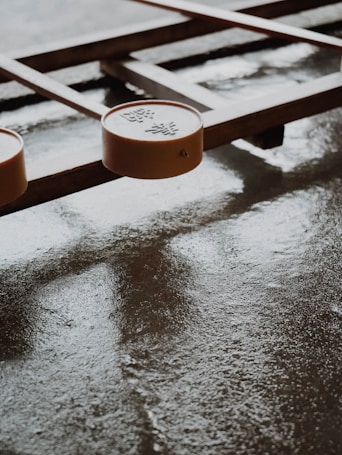 A board game with wooden elements and round pieces featuring Chinese characters. The surface is smooth and slightly reflective, suggesting it might be wet or polished.