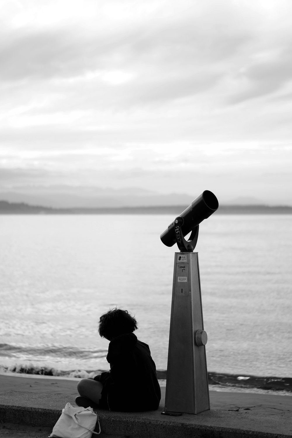 a person sitting on a ledge looking at the water