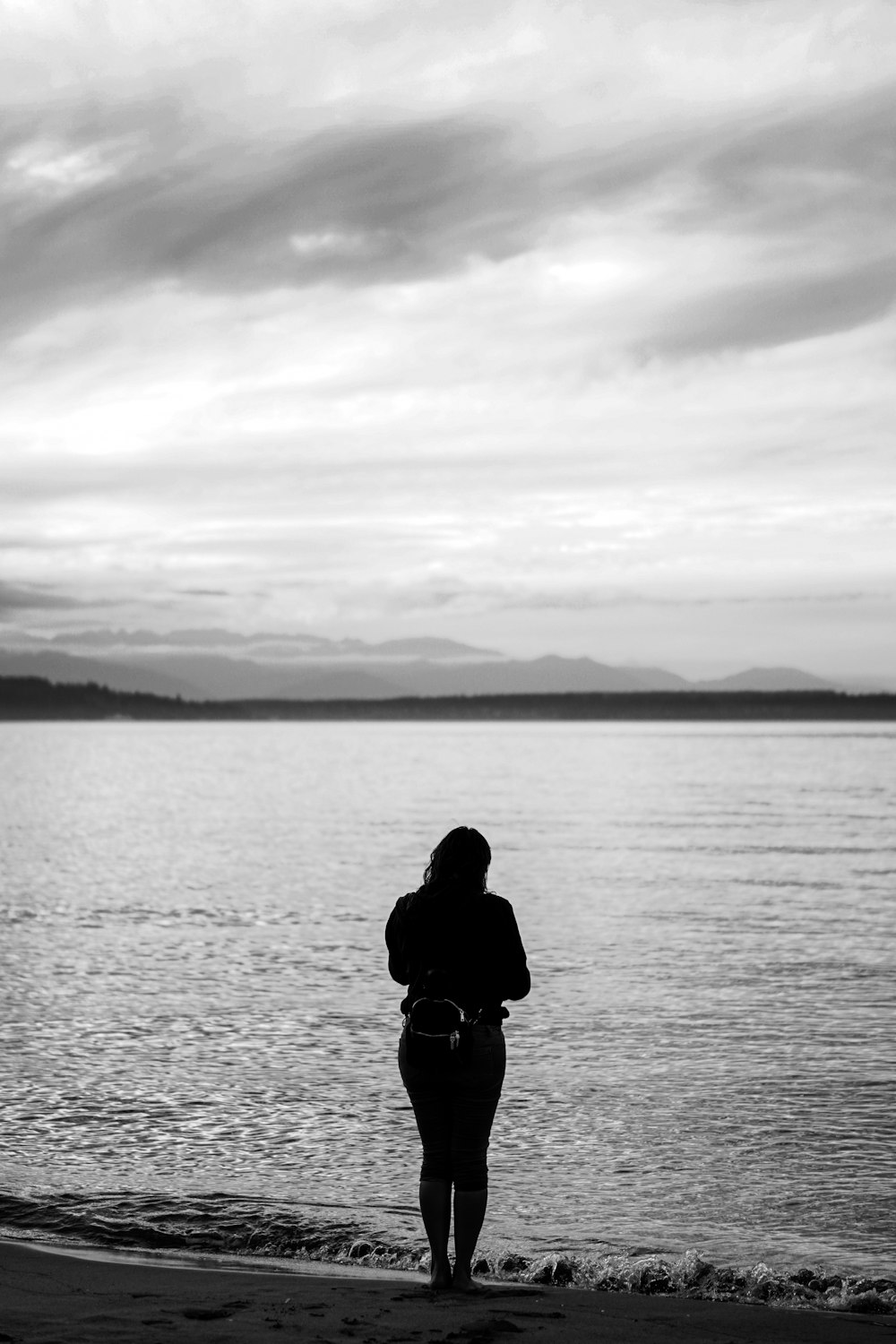 a woman standing on a beach next to a body of water