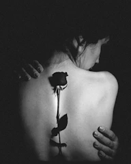 Black and grey tattoo of a delicate rose with intricate shading on the shoulder.