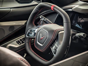 Custom steering wheel wrapped in rich black leather with detailed red stitching
