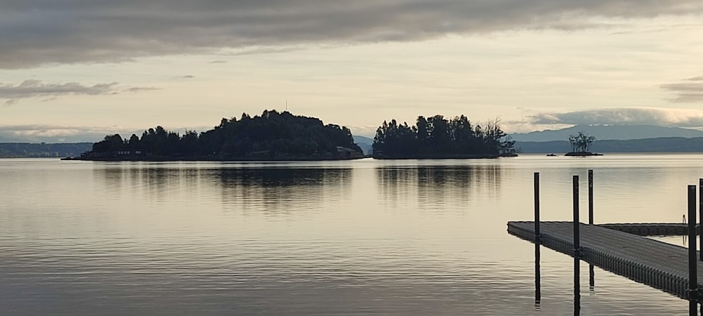 a dock sitting on top of a lake under a cloudy sky