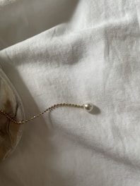 Close-up of a delicate, anti-tarnish gold necklace resting softly on a white linen cloth, highlighting minimalist design.
