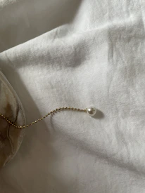 Minimalist necklace displayed elegantly on a light beige textured surface with subtle gold accents.