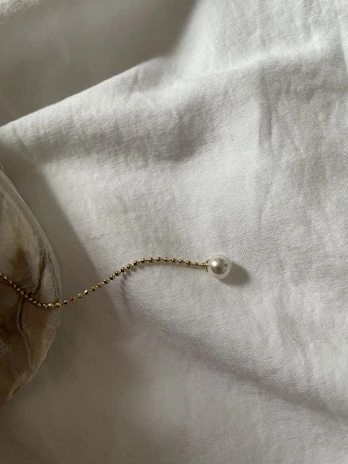 A single strand of shimmering gold beads gently coiled on crisp white linen