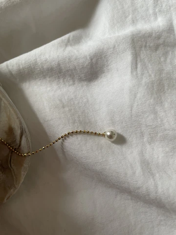 Minimalist necklace displayed elegantly on a light beige textured surface with subtle gold accents.