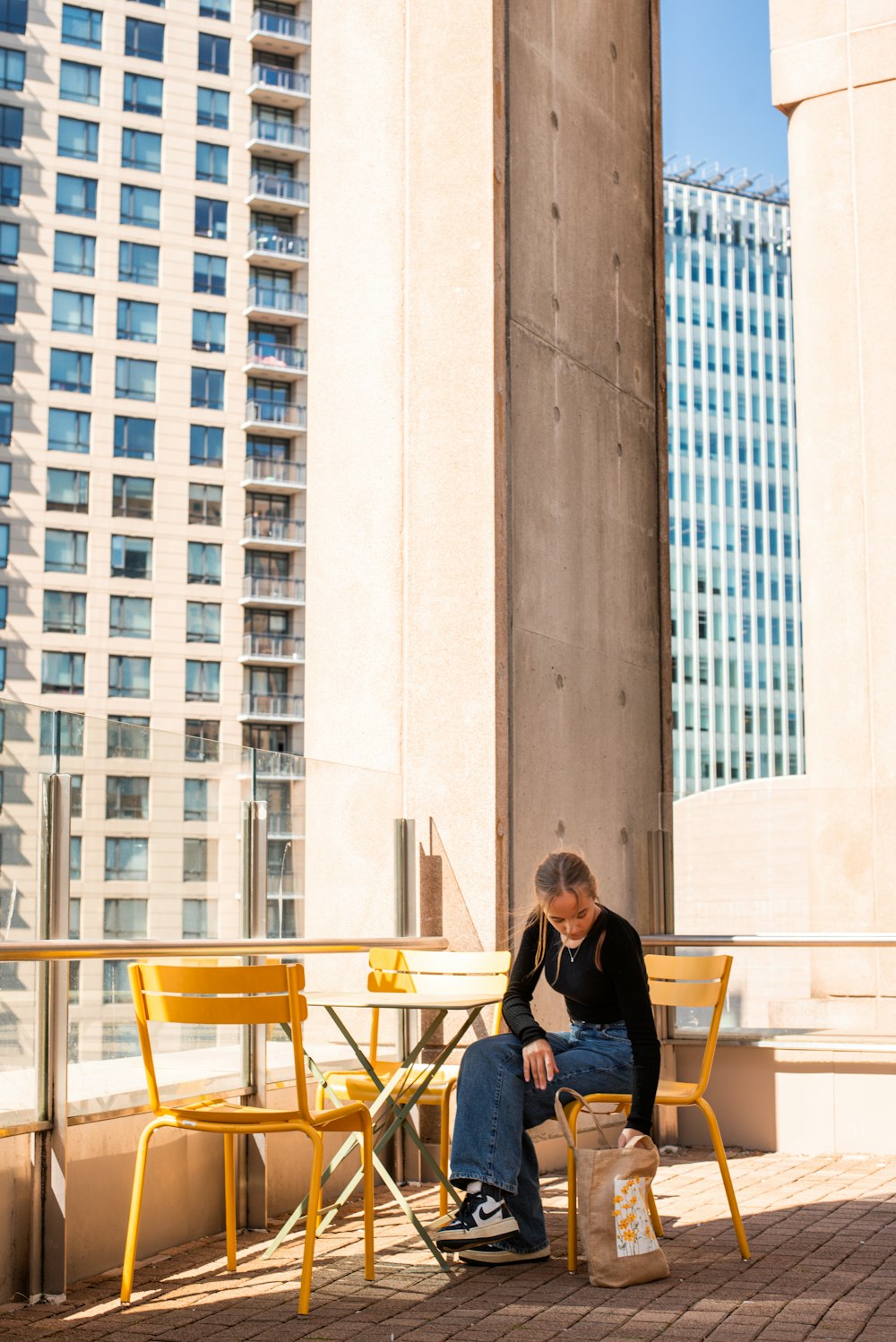 a man sitting on a yellow chair in front of a tall building