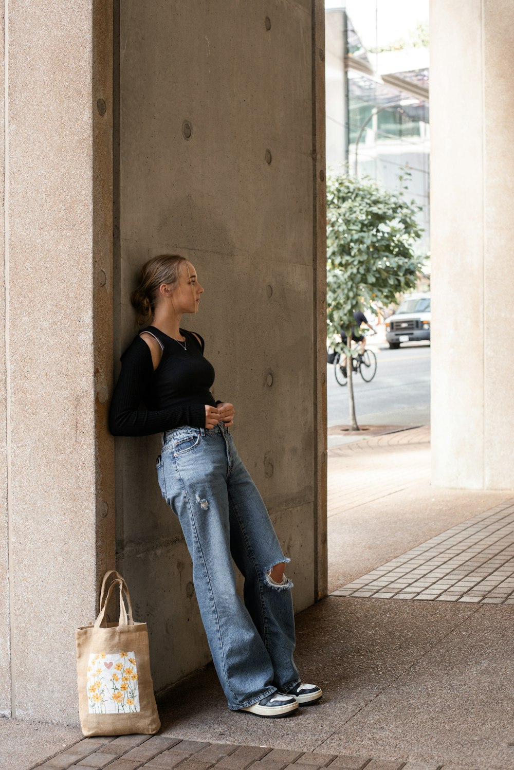 a woman leaning against a wall with her hand on her hip