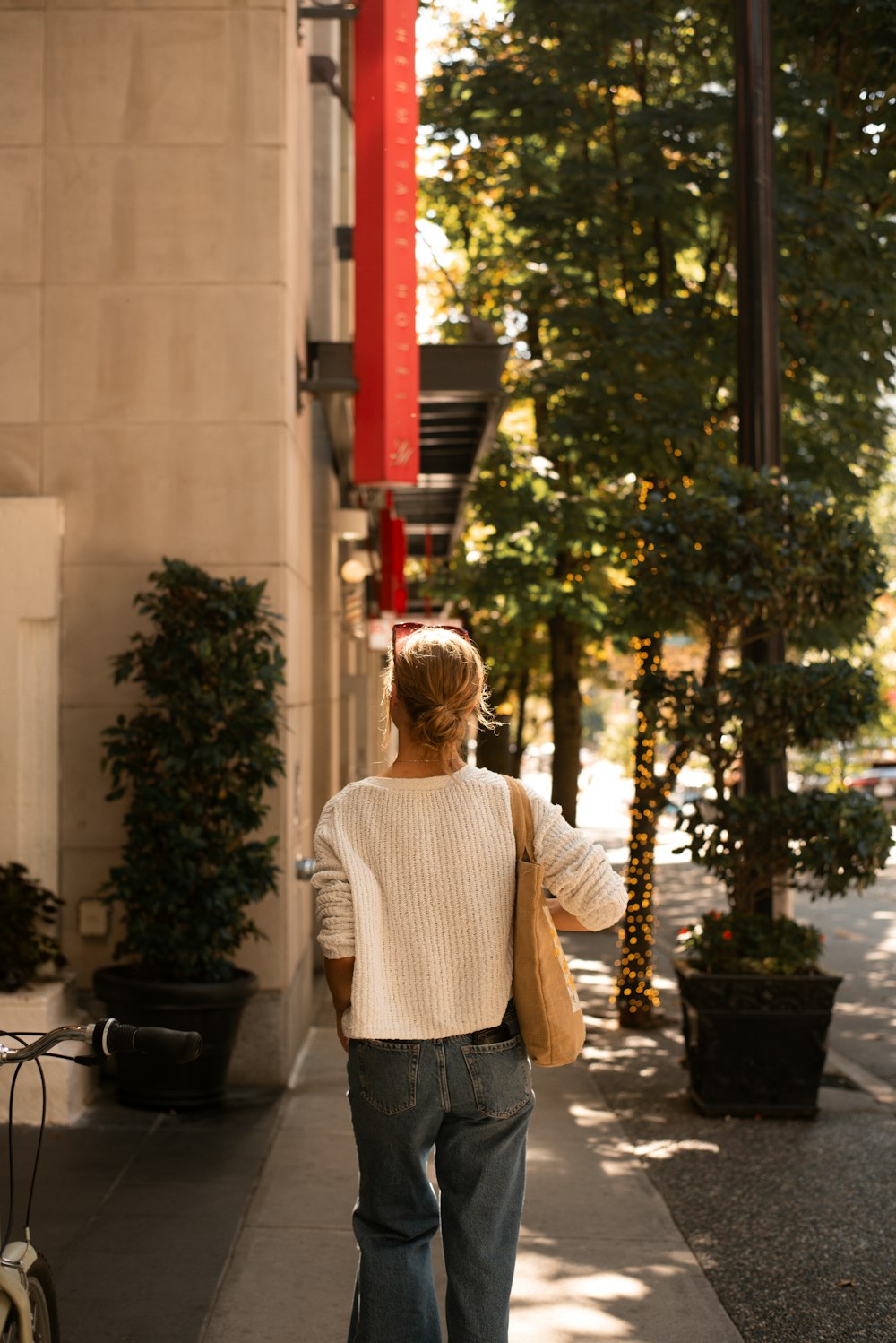 a woman walking down a sidewalk next to a tall building
