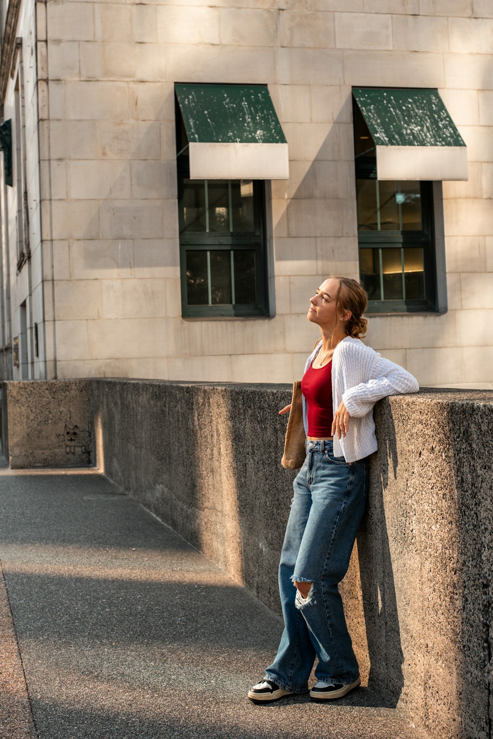 a woman leaning against a wall in front of a building