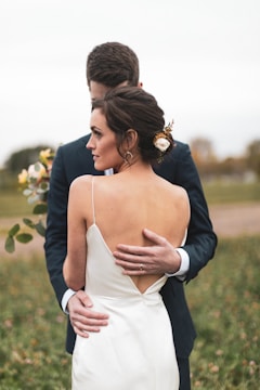 Elegant wedding couple embracing outdoors with warm, natural tones.