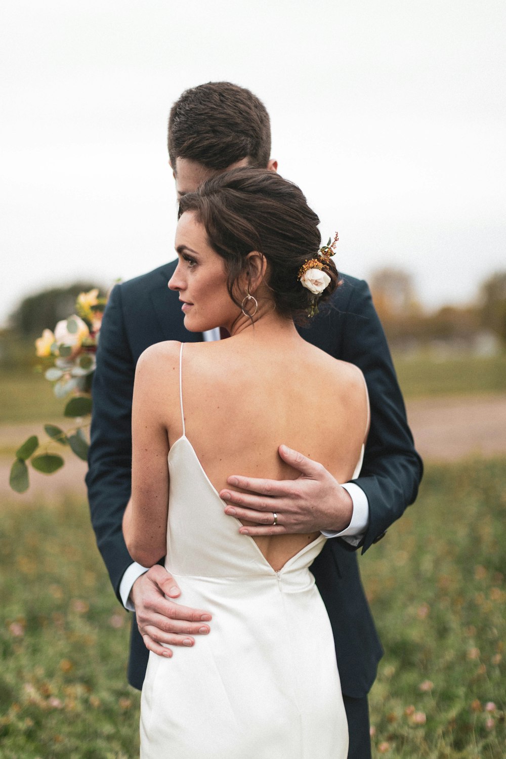 a bride and groom standing in a field