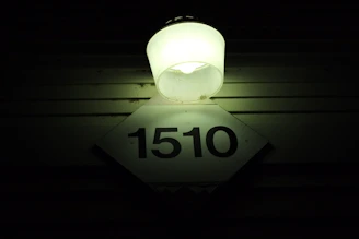 A brightly painted reflective house number glowing clearly at night on a suburban curb.