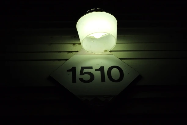 A brightly painted reflective house number glowing clearly at night on a suburban curb.