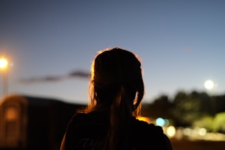 Lyra Grace walking through a twilight cityscape, her silhouette glowing softly.