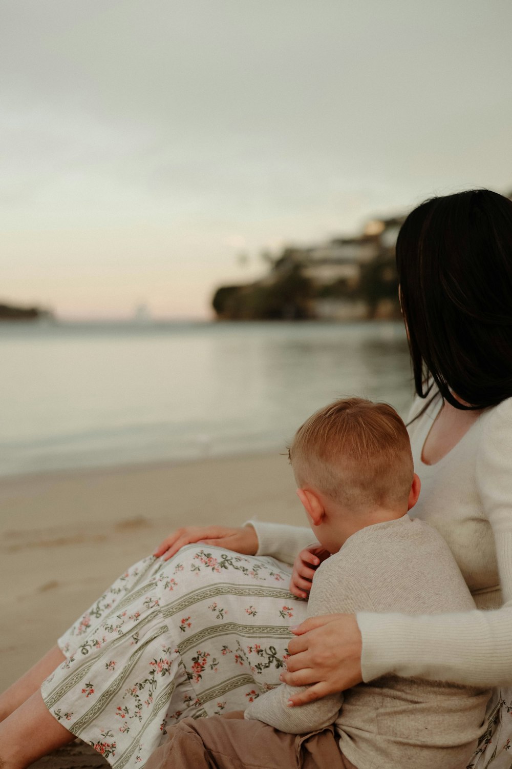 a woman holding a baby on the beach