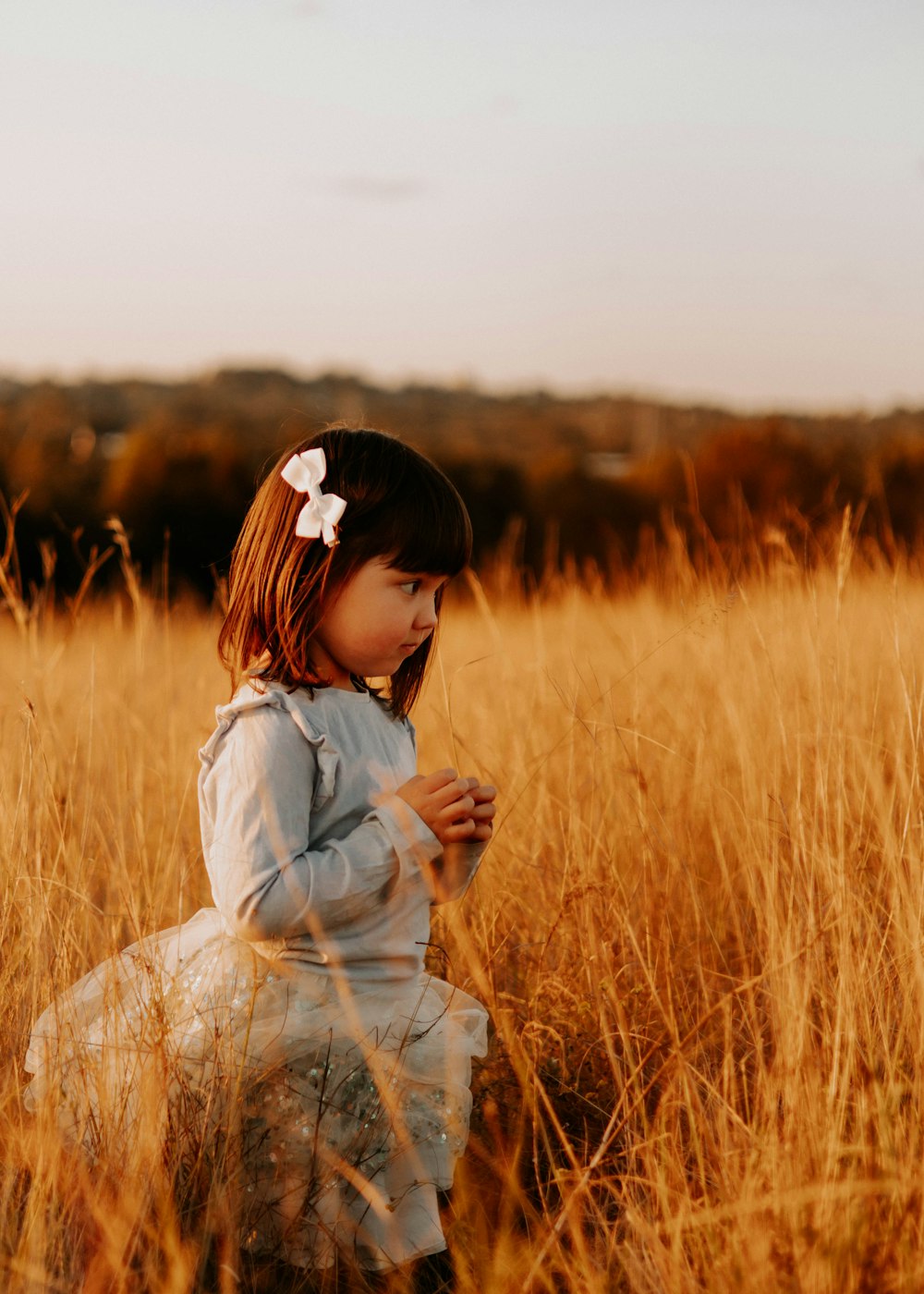 a little girl standing in a field of tall grass