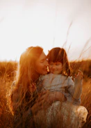a woman holding a small child in a field