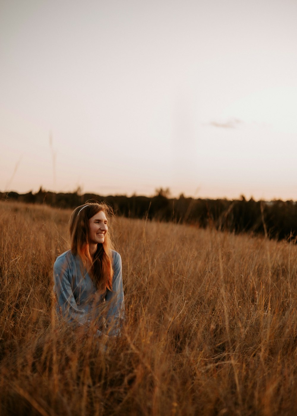 a woman sitting in a field of tall grass