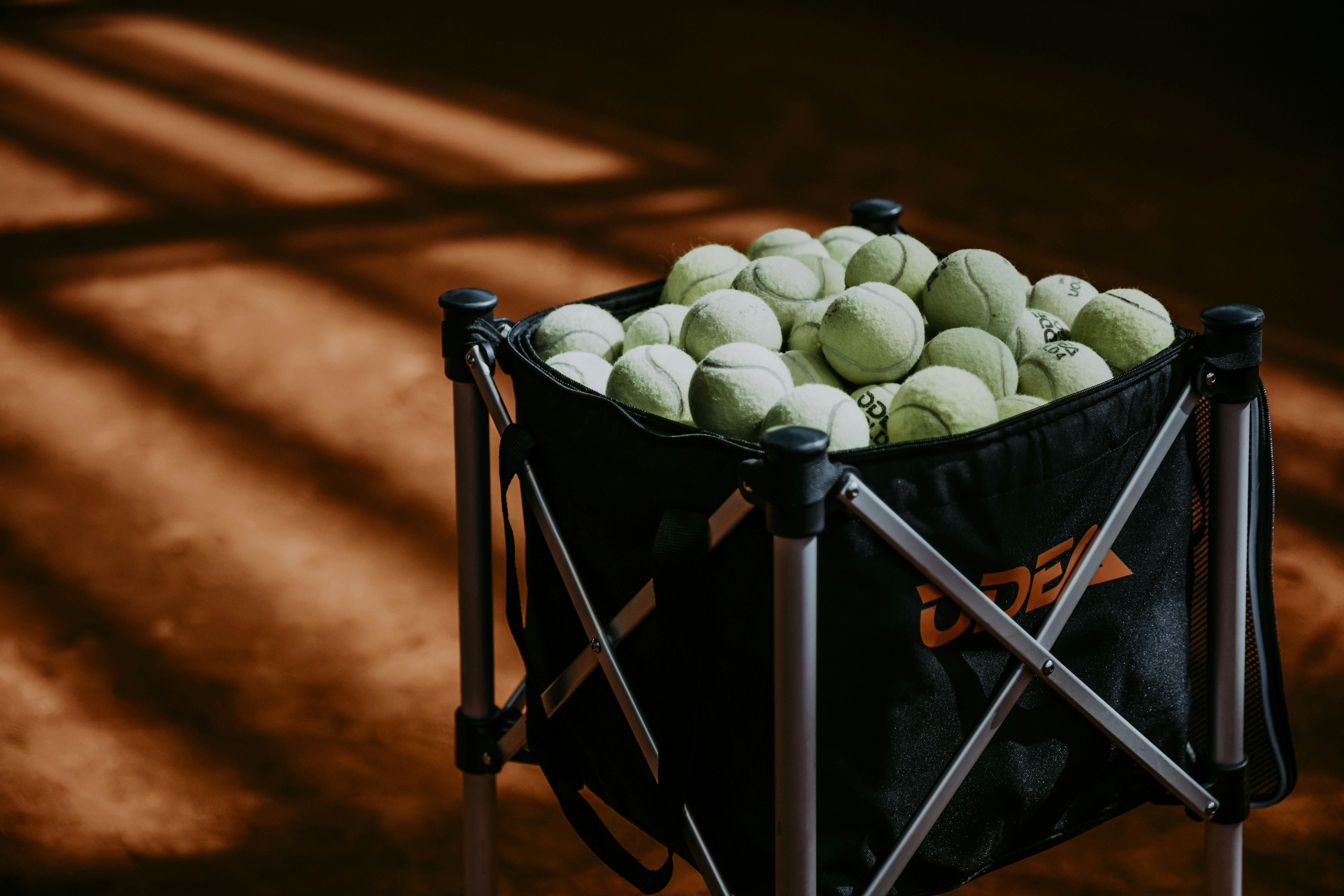 a black bag filled with tennis balls on top of a tennis court