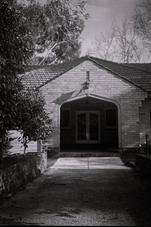 Black and white photo of the family who lived in the house during the 1950s, smiling on the front porch.