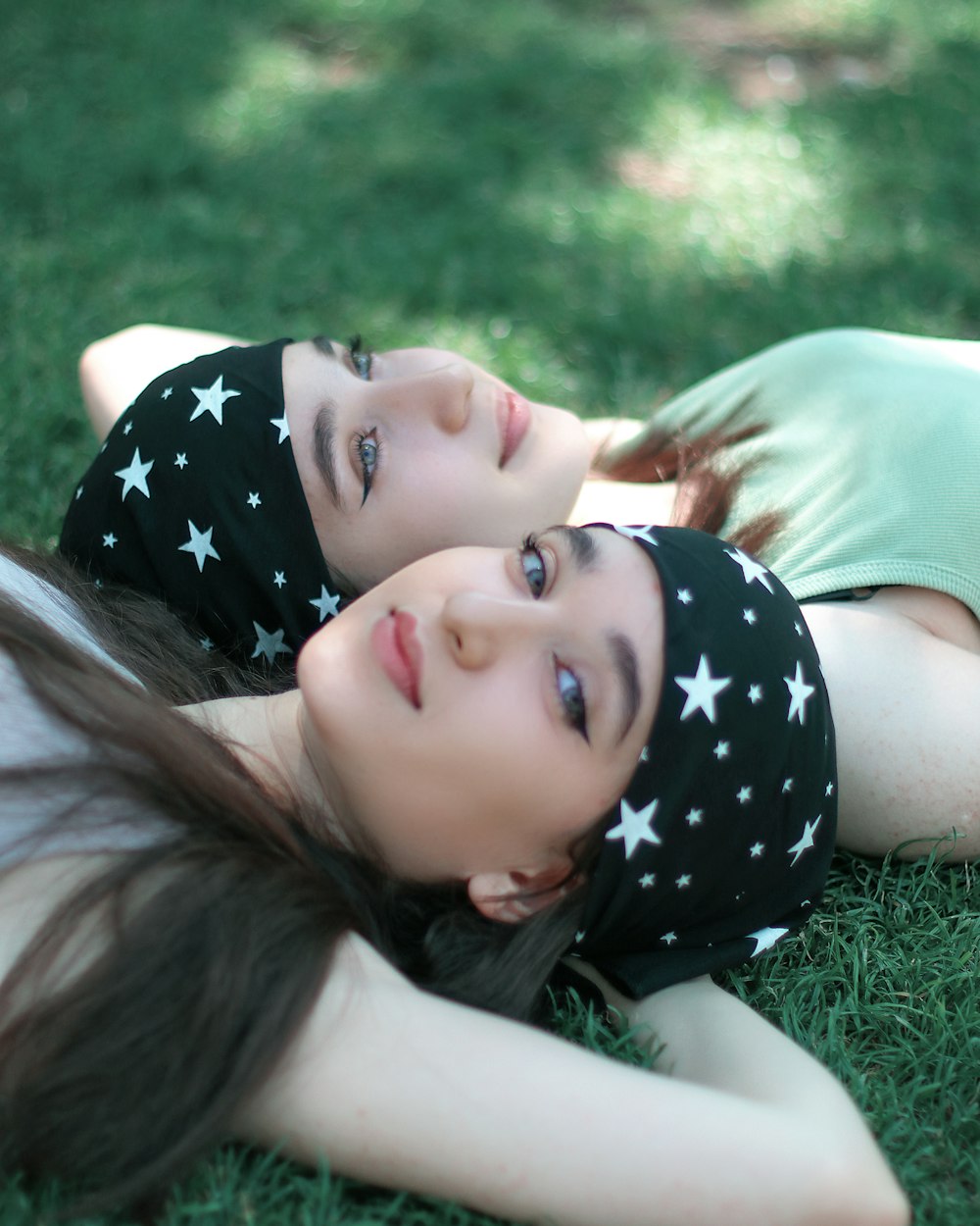 two young girls laying on the grass together