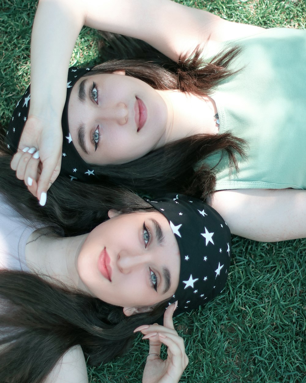 two young women laying on the grass posing for a picture