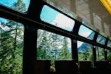 Interior shot of the Whoosh train's first-class cabin featuring plush seats and large windows framing tropical scenery.