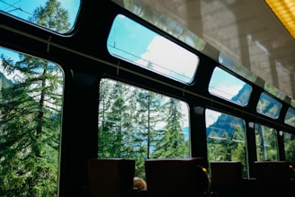 A cozy train interior with comfortable seats and large windows showing scenic views.