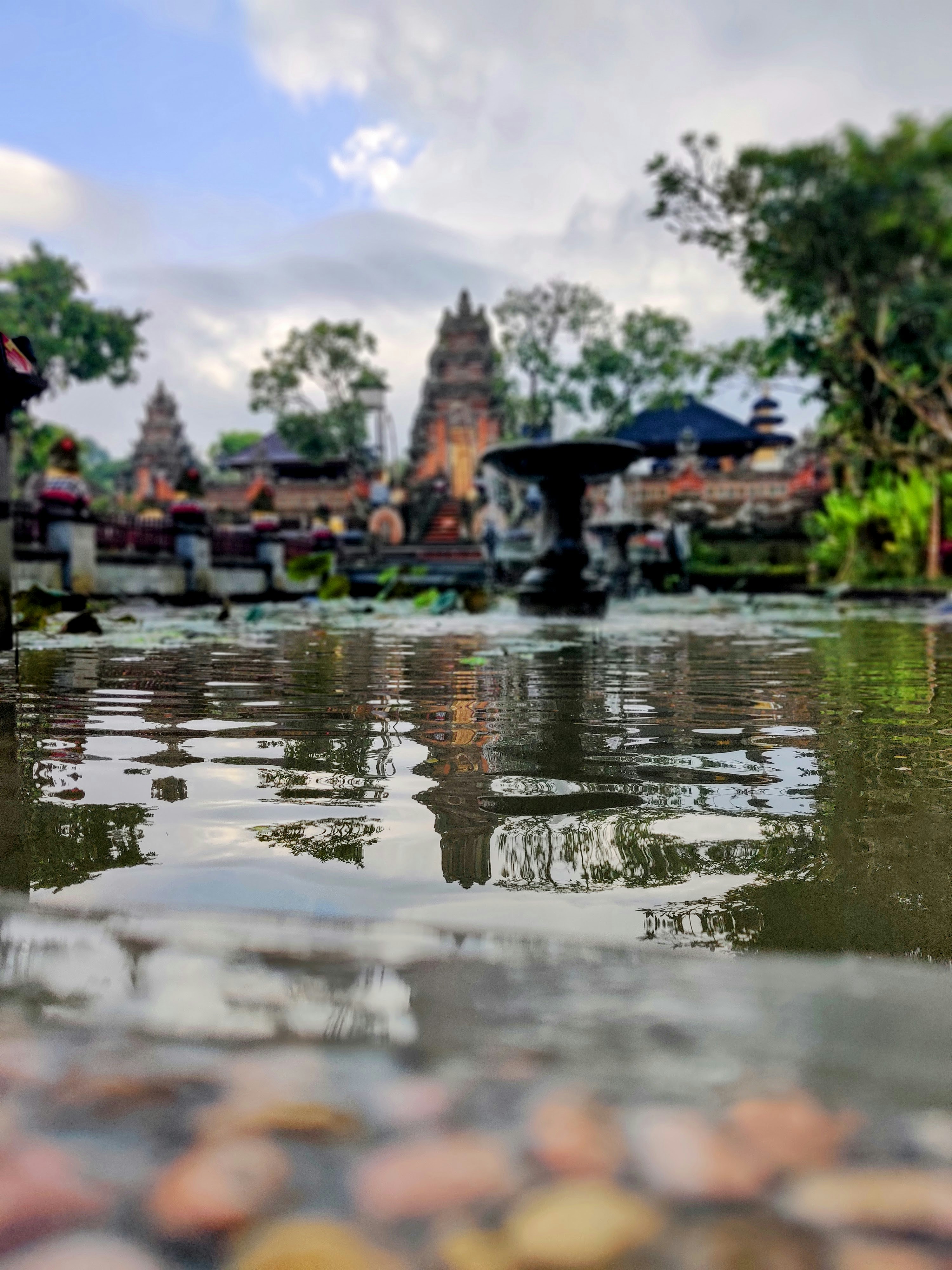 Tempio balinese con fiori di loto in primo piano e vegetazione tropicale lussureggiante