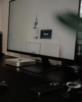 A minimalist metal stand supporting a large screen in a bright office setting.