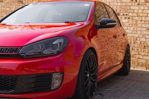 A shiny red car with flawless paintwork parked outside the shop