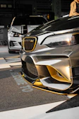 Close-up of a sleek black car with a flawless gold wrap shining under studio lights.