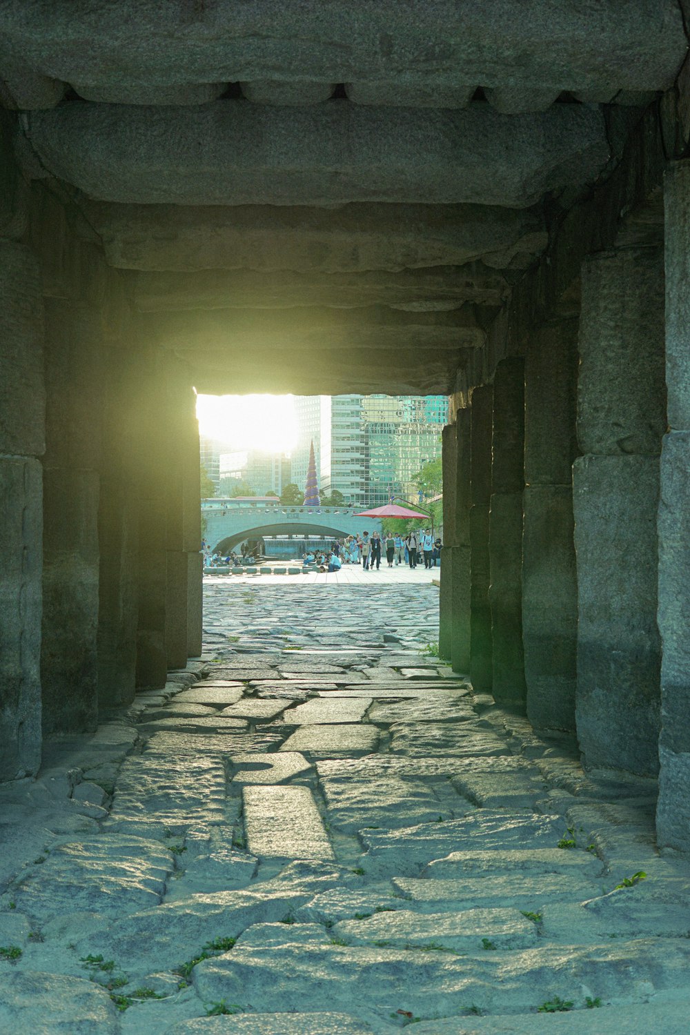 a stone walkway with a light at the end