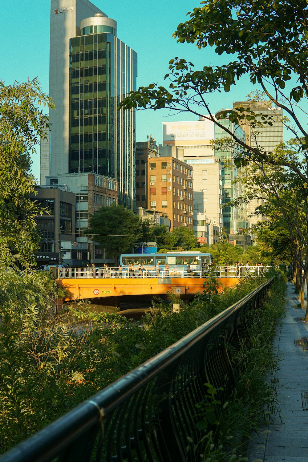 a yellow bridge over a river next to tall buildings