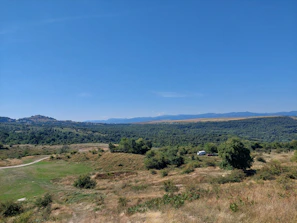 A panoramic view of a peaceful equestrian landscape with a transport van in the distance.
