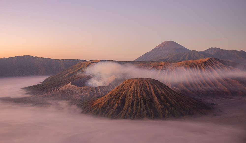 a view of a mountain range with fog in the air