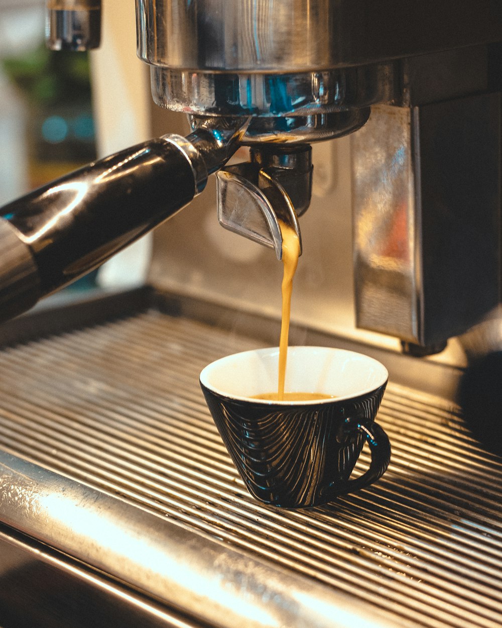 a cup of coffee being poured into a coffee machine