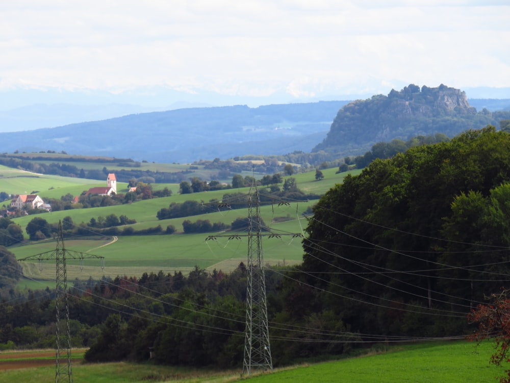 a lush green hillside with power lines in the foreground