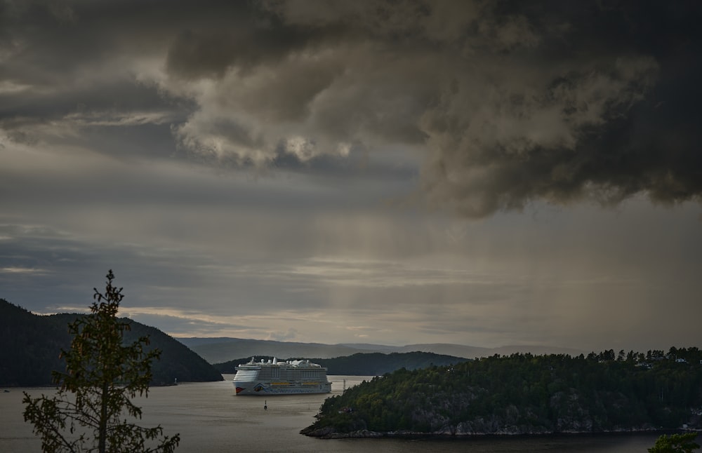 a cruise ship in a body of water under a cloudy sky