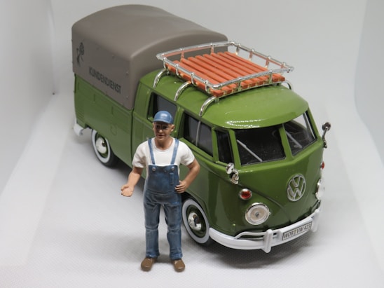 a toy man standing next to a green van