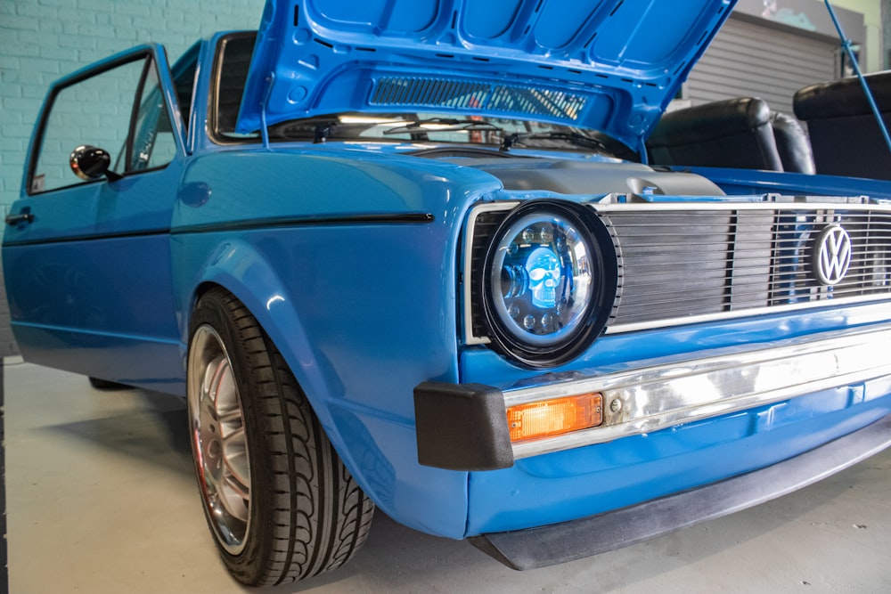 a blue car with its hood open in a garage